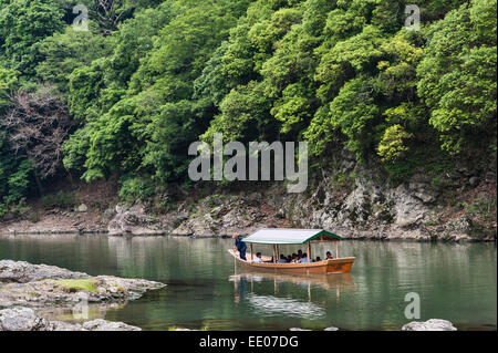 Touristen, die eine Bootsfahrt entlang des Katsura Flusses in Arashiyama, Kyoto, Japan machen Stockfoto