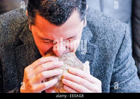 Belfast, Nordirland. 12. Januar 2015. Ein Kunde nimmt einen Bissen des "Tayto Käse und Zwiebel Belfast Bap" bei der Eröffnung des weltweit ersten "Knackig Sandwich" Café. Bildnachweis: Stephen Barnes/Alamy Live-Nachrichten Stockfoto