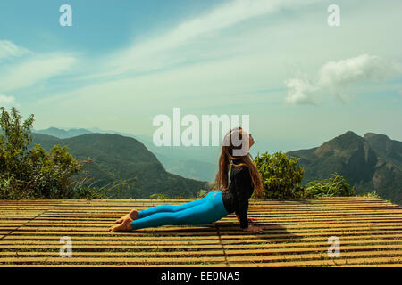 Junge Frau tut Yoga auf einer Plattform am Ende der Welt in Sri Lanka Stockfoto