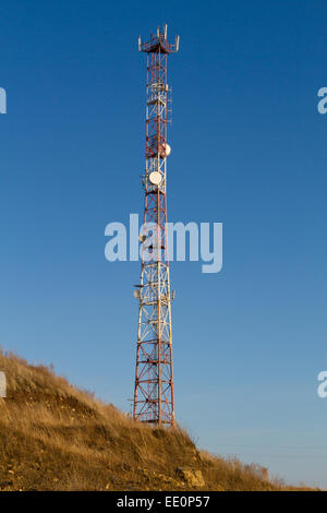 Antennenmast auf blauen Himmelshintergrund isoliert. Fernmeldeturm auf einem Hügel Stockfoto