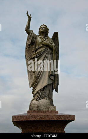 Geschnitzte Engel auf einem Marmorsockel mit Arm gestreckt nach oben. Stockfoto