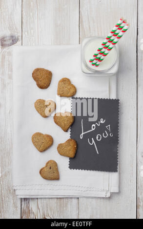 Herzförmige Kekse, Milch und handgeschriebene Karte "Liebe dich" Stockfoto