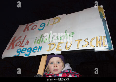 01.05.2015. Köln, Deutschland. Im Bild: Gegendemonstrant innen - hält ein kleines Mädchen ein Plakat gegen die "Idioten deutschen Unterstützung Kögida". Etwa zwei hundert rechtsextreme Demonstranten folgte einem Ruf zu demonstrieren gegen die Islamisierung Europas in Köln. KÖGIDA Demonstranten wurden von Tausenden von linksgerichteten Demonstranten weit unterlegen. Dies folgt der PEGIDA-Demonstrationen in Dresden, die eine große Zahl von Anhängern anzuziehen, zu halten. PEGIDA steht für "Patriotischen Europäische gegen die Islamisierung Europas". Kölner Dom - in der Regel nachts beleuchtet - blieb als Protest da Stockfoto