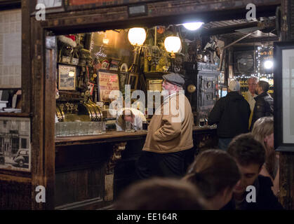 Die Bar im McSorley es Old Ale House. Ein Mann steht an der Bar, während der Barkeeper etwas unter der Theke holt Stockfoto
