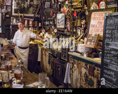 Hinter der Bar im McSorley es Old Ale House. Der Barkeeper und die unübersichtlichen Wände von Ausrüstung und Erinnerungsstücke hinter der bar Stockfoto