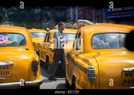 Mann überquert eine Straße, zu Fuß durch gelbe Taxis während einer Verkehrsstaus in Kalkutta, West Bengal, Indien. Stockfoto