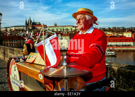 Senior man Musiker spielen auf Tonnenorgel, Karlsbrücke Prager Burg Tschechische Republik Europa Busker Straßenmusiker Prager Musiker Österreichische Flagge Stockfoto