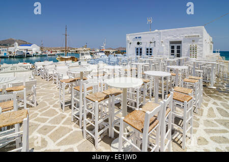 Tischen entlang der Uferpromenade Taverne ist von Naoussa Stadt, Insel Paros, Kykladen, Griechenland Stockfoto