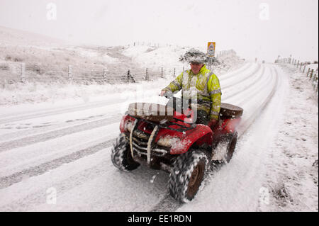 Mynydd Epynt Reihe von Hügeln, Powys, Wales, UK. 13. Januar 2015. Ein Landwirt trotzen Wetter auf seinem Quad-Bike auf die B4520 "Brecon" Straße über Hochmoor zwischen Builth Wells und Brecon. Schnee fällt in Mid Wales wie vorhergesagt durch die Wettervorhersagen. Bildnachweis: Graham M. Lawrence/Alamy Live-Nachrichten. Stockfoto