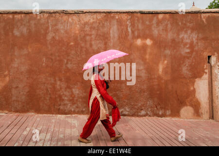 Frau mit Regenschirm durchläuft Eintrag Wand von Agra Red Fort Komplex. Stockfoto