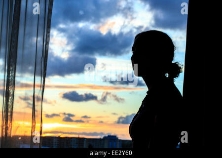 Eine Frau in ihrem Hotelfenster wie die Sonne über Malmö, Schweden. Stockfoto