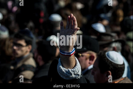 Jeruslaem, Israel. 13. Januar 2015. Ein Mann hebt seine Hand mit einer Band der französischen Nationalflagge an seinem Handgelenk während einer Trauerfeier für die vier Opfer von Paris Supermarkt Angriff auf Givat Shaul Friedhof am Stadtrand von Jerusalem, am 13. Januar 2015. Israelische Führung und Vielzahl von Trauernden Dienstag mit den Familien der vier jüdische Opfer der letzten Woche Terror-Anschlag auf einen Paris koscheren Supermarkt für einen feierlichen Trauerfeier auf einem Friedhof in Jerusalem versammelt. Yoav Hattab, Yohan Cohen, Philippe Braham und Francois Michel Saada, am Freitag während einer Geisel Atta niedergeschossen wurden © Xinhua/Alam Stockfoto