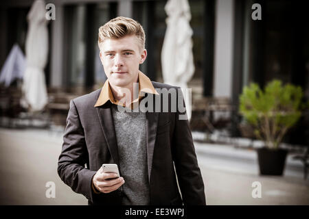 Junger Geschäftsmann mit Handy, München, Bayern, Deutschland Stockfoto