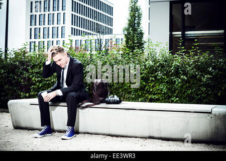 Junge Unternehmer sitzen mit der Hand in den Haaren, München, Bayern, Deutschland Stockfoto
