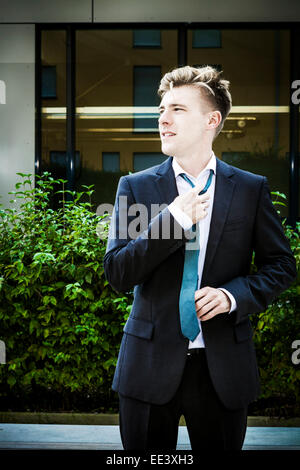 Junger Geschäftsmann Anpassung seine Krawatte, München, Bayern, Deutschland Stockfoto