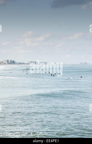 Viele Surfer warten auf eine Welle als eine Dünung rollt durch die Daytona Beach, Florida-Skyline im Hintergrund. Stockfoto