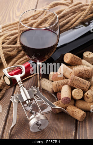 Glas Rotwein, Flasche, Haufen von Korken und Korkenzieher auf rustikalen Holztisch Stockfoto