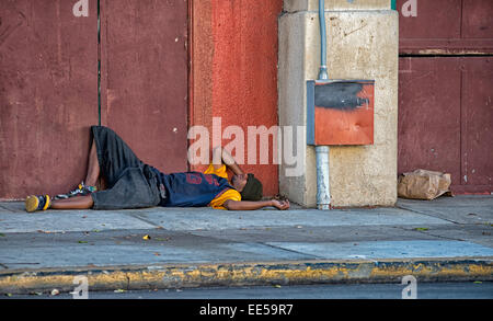 Mann schläft auf Bürgersteig neben Gebäude, East Village, San Diego, Kalifornien USA Stockfoto