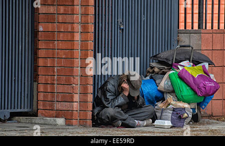 Obdachloser sitzen auf Bürgersteig neben Gebäude und Karren, East Village, San Diego, Kalifornien USA Stockfoto