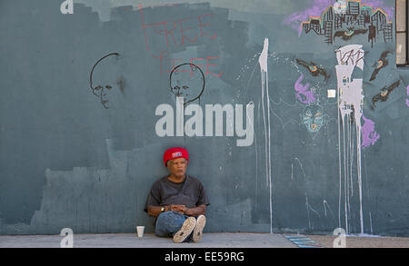 Mann sitzt auf dem Bürgersteig gegen Gebäude, East Village, San Diego, Kalifornien USA Stockfoto