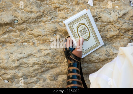 JERUSALEM, ISRAEL - 6. Oktober 2014: Ein jüdischer Mann mit der Thora in seiner Hand und Tefillin um seinen Arm gegen die Wes betet Stockfoto