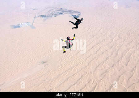 Zwei Fallschirmspringer bilden die Sit-fliegen-Position über eine große Wüste Bereich. Frage mich, wohin sie danach landen? Stockfoto