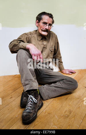 Der Mensch in seiner 60er Jahre mit Schnurrbart tragen khakifarbene Hemd und Hose auf dem Boden sitzen. Stockfoto