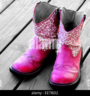 Detail der rosa Cowgirl Cowboy-Stiefel auf Holzdeck für ein Mädchen Stockfoto