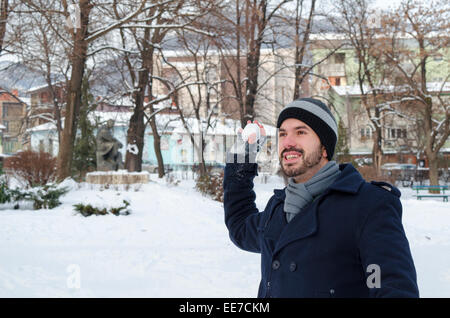 Junger Mann warf einen Schneeball in einem verschneiten park Stockfoto