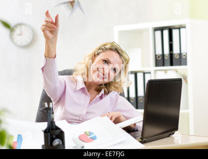 Geschäftsfrau werfen Papierflieger im Büro Stockfoto