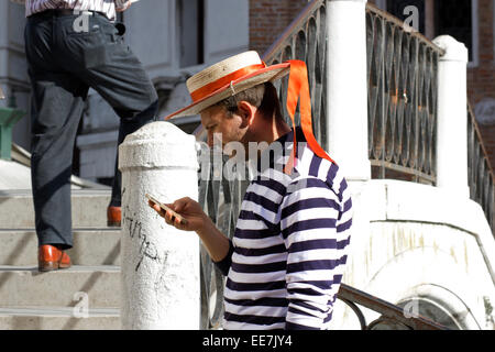 Gondoliere Überprüfung seines Mobiltelefons. Venedig, Italien Stockfoto