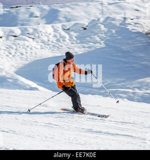 Skifahrer mit Rucksack Skifahren auf der Piste im Wintersportort in den Alpen Stockfoto