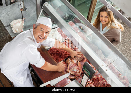 Metzger und Kunden lächelnd in Vitrine Stockfoto