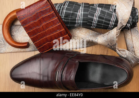 Klassische Herren Schuhe, Krawatte, Brieftasche, Regenschirm auf dem Holzboden kann als Hintergrund verwendet werden Stockfoto