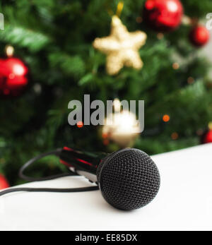 Schwarz Mikrofon auf weißem Ledersofa in der Nähe der Weihnachtsbaum. Konzept der Song Weihnachtsmusik. Stockfoto