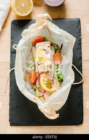 Ein offenes Paket "Papillote" gefülllt mit Lachsfilet und Gemüse. Gerade gebacken. Stockfoto