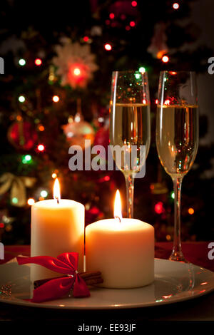 Feiern Weihnachten dekoriert Weihnachten Esstisch mit Sektgläsern und Weihnachtsbaum im Hintergrund Stockfoto