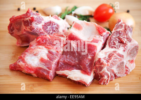 Rohes Rindfleisch mit Gewürzen und Gemüse auf dem Schneidebrett Stockfoto