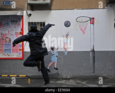 (150115)--CHANGSHA, 15. Januar 2015 (Xinhua)--ein Mann macht ein shooting vor einem Basketball-Cartoon posieren Wandbild in einer Wohnanlage von Changsha, der Hauptstadt der Provinz Zentral-China Hunan, 15. Januar 2015. Die Außenwände der Wohnanlage in Changsha haben verjüngt, nachdem eine Gruppe von jungen Karikaturisten wurden eingeladen, einige 40 Cartoon Wandbilder auf ihnen zu schaffen. Die Fototapete Maler zeichnete nicht nur auf normale Wände, sondern auch gemischt ihre Arbeit mit der Umwelt durch die Integration der Objekte in der Szene (Zeitung-Boxen, Strom Messgerät Fällen, Klimaanlage Einheiten, etc.) in der Stockfoto