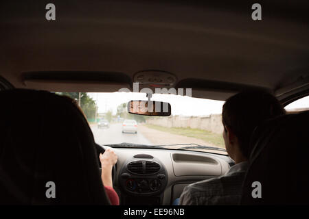 junge Frau in Auto - indoor hält Rad drehen rund Blick auf Passagiere sitzen Seite Idee von Taxi Driver im Gespräch mit der Polizei Stockfoto