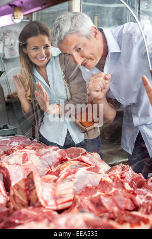 Paar auf der Suche bei Fleisch durch Schrank In Metzgerei Stockfoto