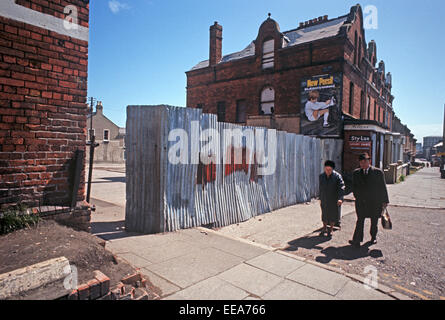 BELFAST, NORDIRLAND - MAI 1972. Paar, vorbei an einer der 1. Frieden Wände zwischen katholischen und evangelischen Gemeinden in Belfast während der Unruhen, Nordirland. Stockfoto
