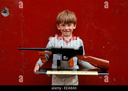 INTERNIERUNG KUNST, LONG KESH, NORDIRLAND - JUNI 1972. Kind hält hölzerne Replik einer Thompson Maschinengewehr, während der Unruhen von Long Kesh Gefangene gemacht. Stockfoto