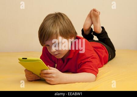 kleiner Junge spielt mit seinem Tablet-PC Stockfoto