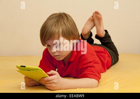 kleiner Junge spielt mit seinem Tablet-PC Stockfoto