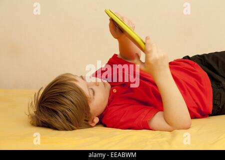 kleiner Junge spielt mit seinem Tablet-PC Stockfoto