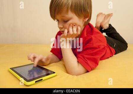 kleiner Junge spielt mit seinem Tablet-PC Stockfoto