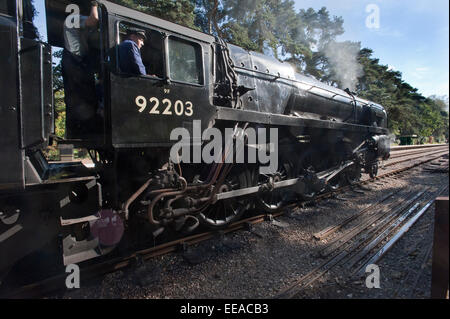 Der Fahrer des 9F 2-10-0 Dampflokomotive Nr. 92203 "Black Prince" Kontrollen die Straße voran wie es läuft Runde seinen Zug Haltestelle Holt auf die North Norfolk Railway zwischen Holt und Sheringham, in der Nähe von Norwich. Stockfoto