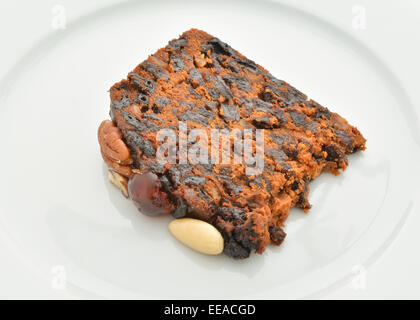 Slice Hausgemachte Früchtekuchen mit Nüssen und Kirschen auf weißem Teller dekoriert Stockfoto