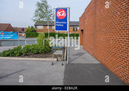 Ein Schild in einem Supermarkt-Parkplatz für ein Motorrad mit einem Einkaufspark Wagen an der falschen Stelle. Stockfoto